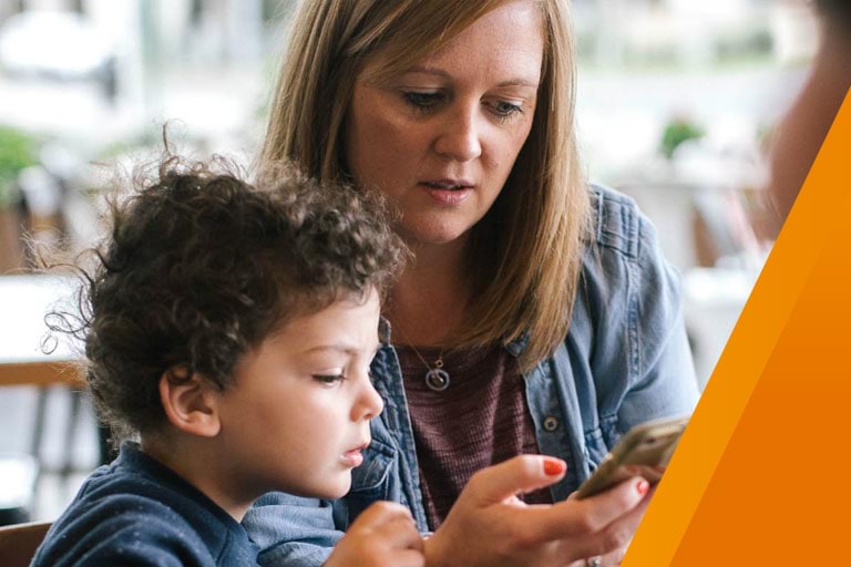 A woman and child looking at the screen of a mobile phone