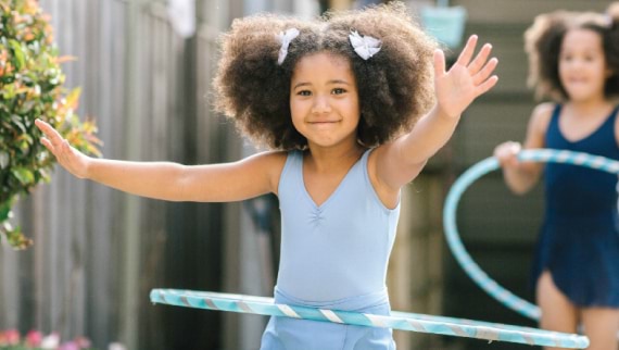 Photo of smiling children using hoola hoops